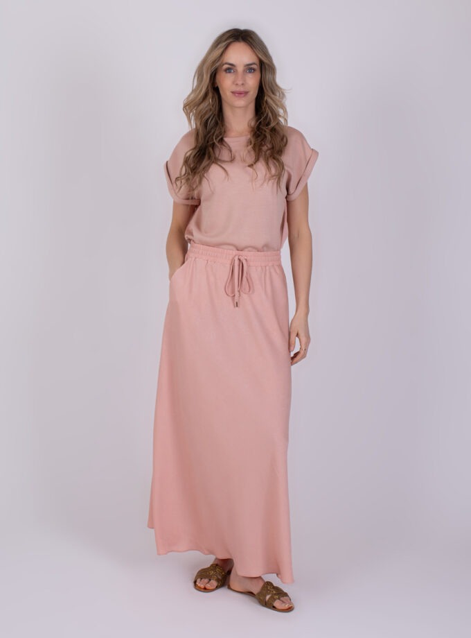 Vrouw draagt een comfortabele, oudroze Aba outfit met een losse top en lange rok.