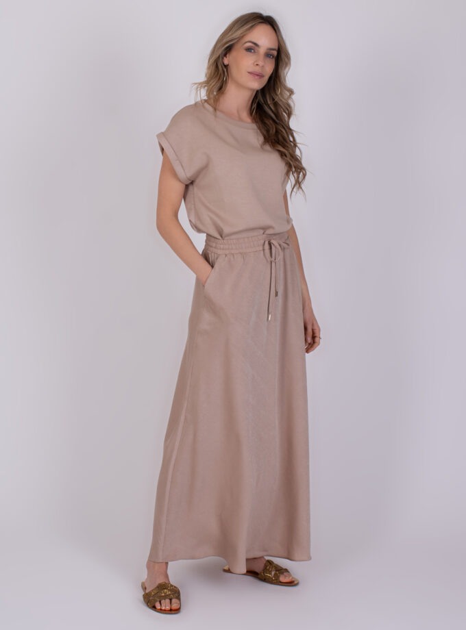 Vrouw draagt een beige Aba Pale 1 outfit met losvallende top en lange rok.