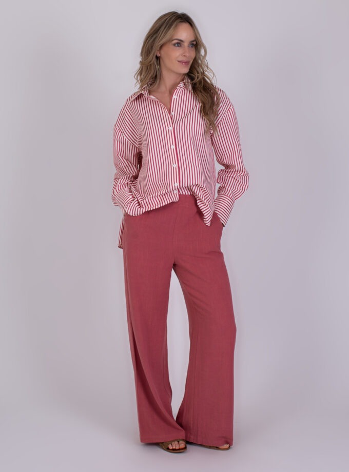 Vrouw draagt een rood-wit gestreeerde blouse en wijde old pink Almeria-broek.