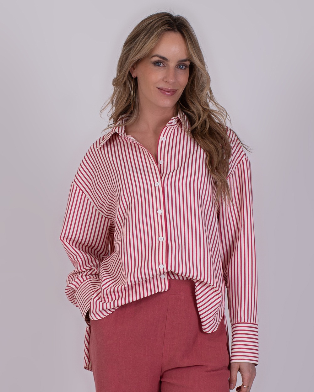 Almeria old pink 3 Vrouw draagt een rood-wit gestreepte blouse en oudroze broek uit de Almeria old pink 3 collectie.