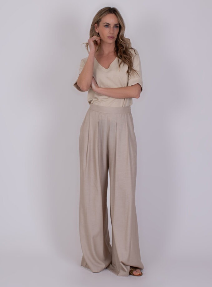 Vrouw draagt een beige Amfissa Pale 4 outfit met een V-hals top en wijde pantalon.