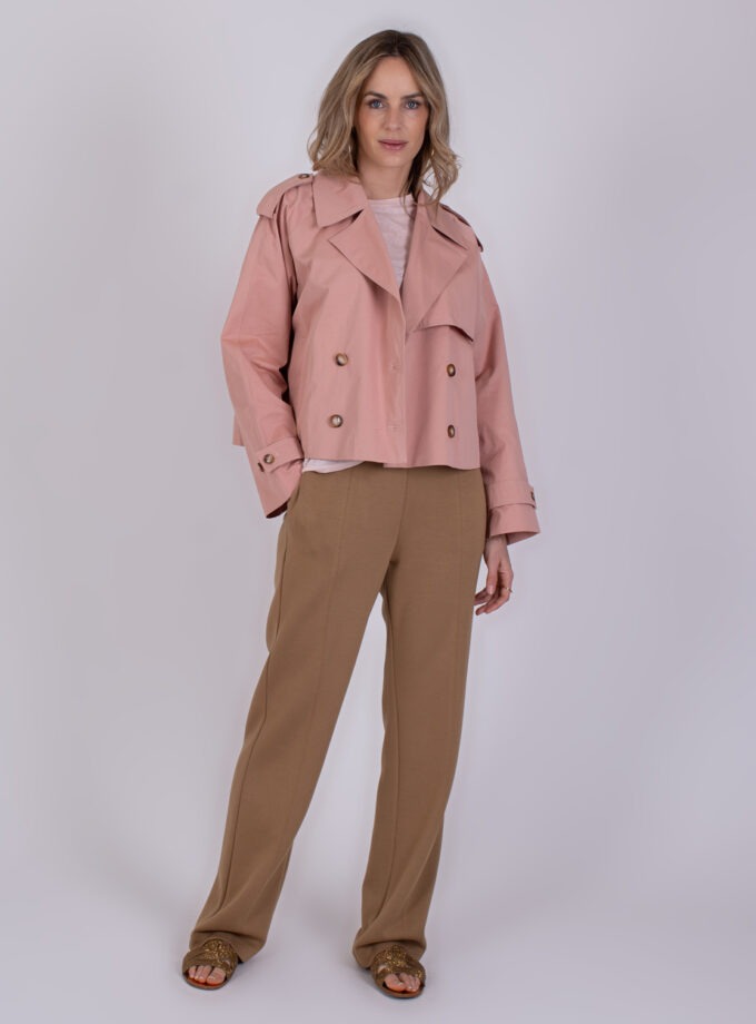Vrouw draagt een cropped Aosta old pink jas met bruine broek en open sandalen.