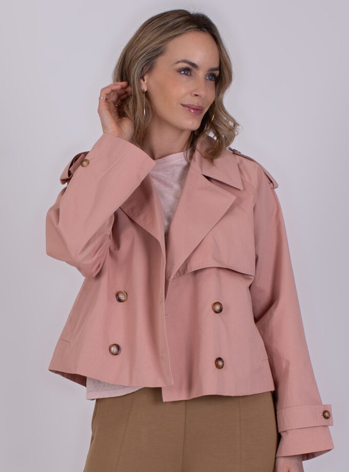 Vrouw draagt een korte, oudroze jas met dubbele knopenrij en wijde kraag, model Aosta old pink.