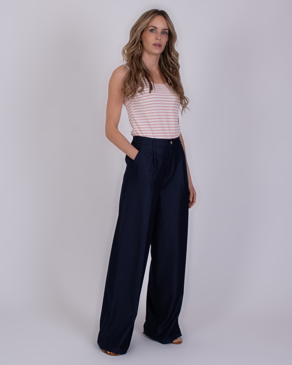 Bergamo Indigo blue 4 Vrouw draagt wijde Bergamo Indigo blue 4 broek met een mouwloos, licht gestreept topje.