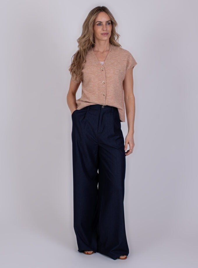 Vrouw draagt een beige mouwloos vest en wijde Bergamo Indigo blue 7 broek.