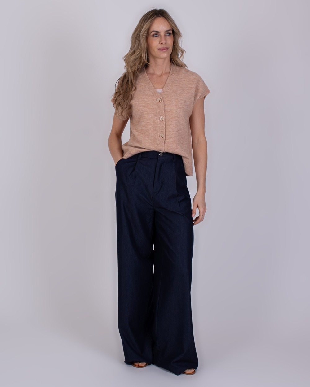 Bergamo Indigo blue 7 Vrouw draagt een beige mouwloos vest en wijde Bergamo Indigo blue 7 broek.