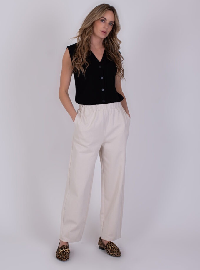 Vrouw draagt een zwarte mouwloze top en off-white Bilbao broek met rechte pijpen en luipaardprint loafers.