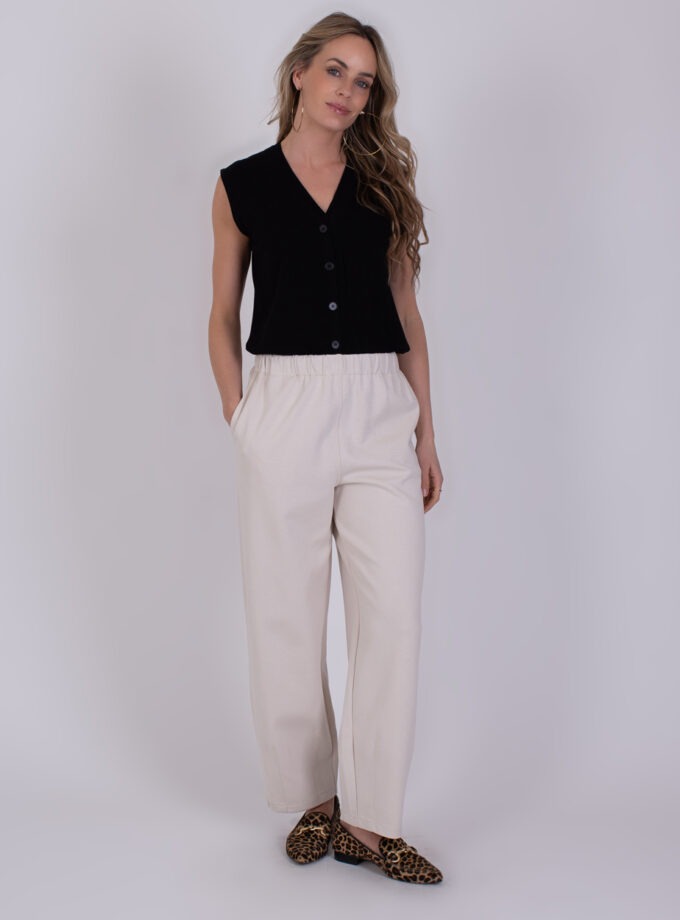 Vrouw draagt een zwarte mouwloze top met knopen, off-white Bilbao broek en panterprint loafers.