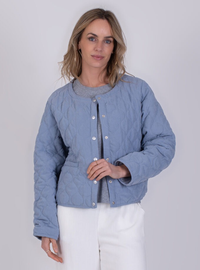 Vrouw draagt een licht gewatteerd jack genaamd Burgas Soft Blue in een zachte blauwe kleur.