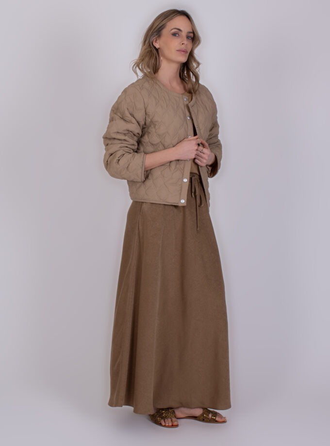 Vrouw draagt een taupekleurige quilted jas en lange rok uit de Burgas taupe collectie.