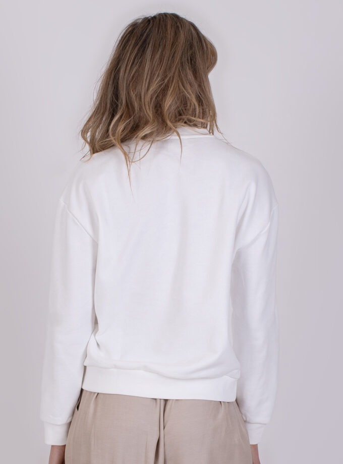 Achteraanzicht van een persoon die een offwhite Capri-trui en beige broek draagt.