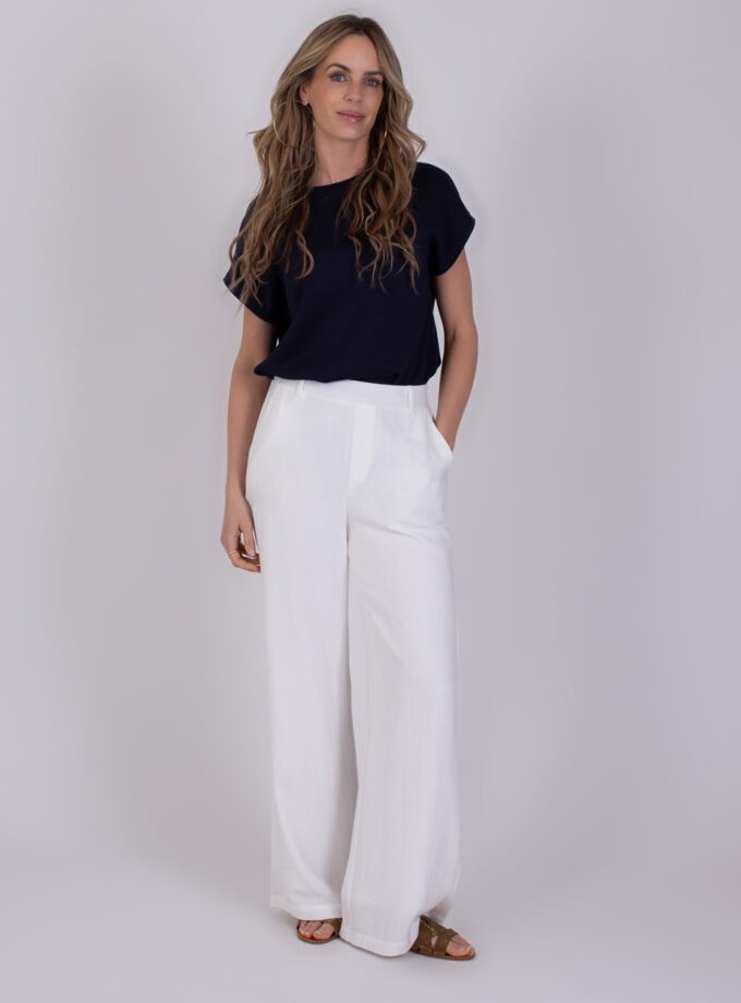 Vrouw draagt een zwarte top en een witte, wijde Cebu-off-white broek met sandaalhakken.