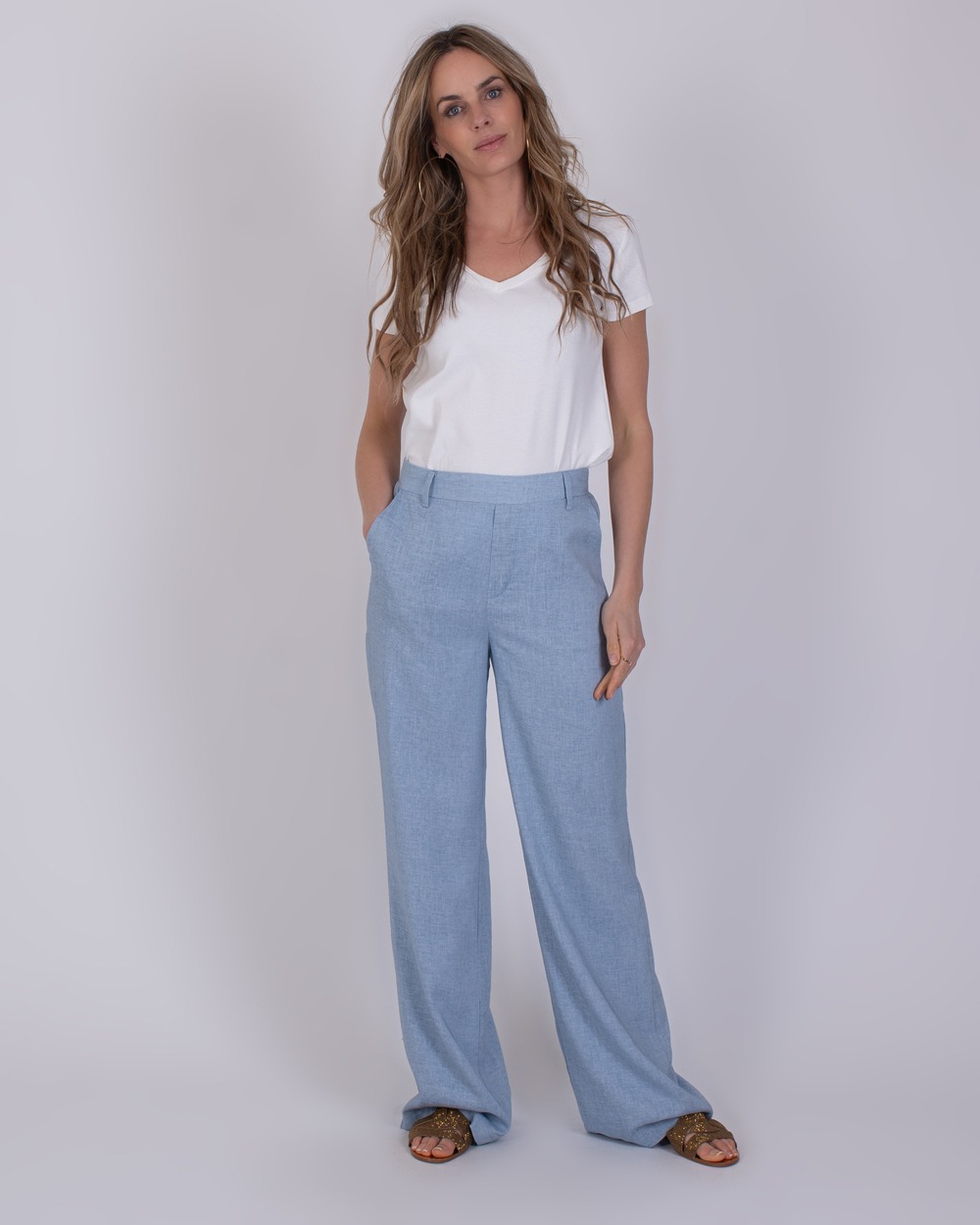 Vrouw draagt een witte V-hals T-shirt en lichtblauwe wijde broek genaamd Cebu soft blue.