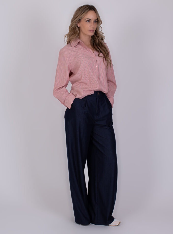Vrouw draagt een roze gestreeerde blouse genaamd "Chennai old pink 5" en wijde, donkerblauwe broek.