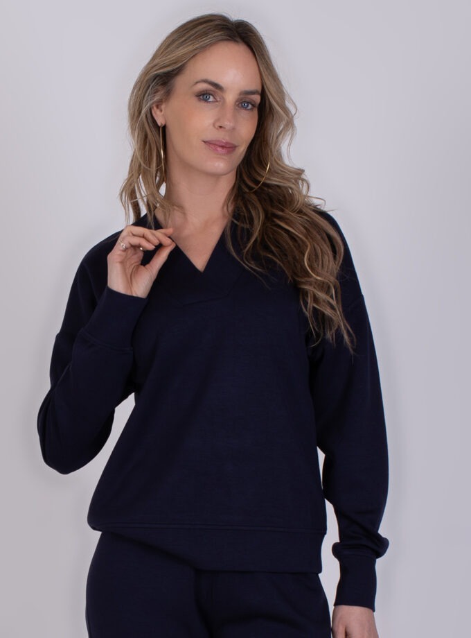 Vrouw draagt een donkerblauwe Chester Navy trui met V-hals en lange mouwen.