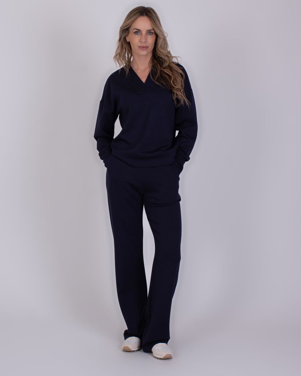 Chester navy 3 Vrouw draagt een donkerblauwe Chester Navy 3 loungewear-set met lange mouwen en wijde broekspijpen.