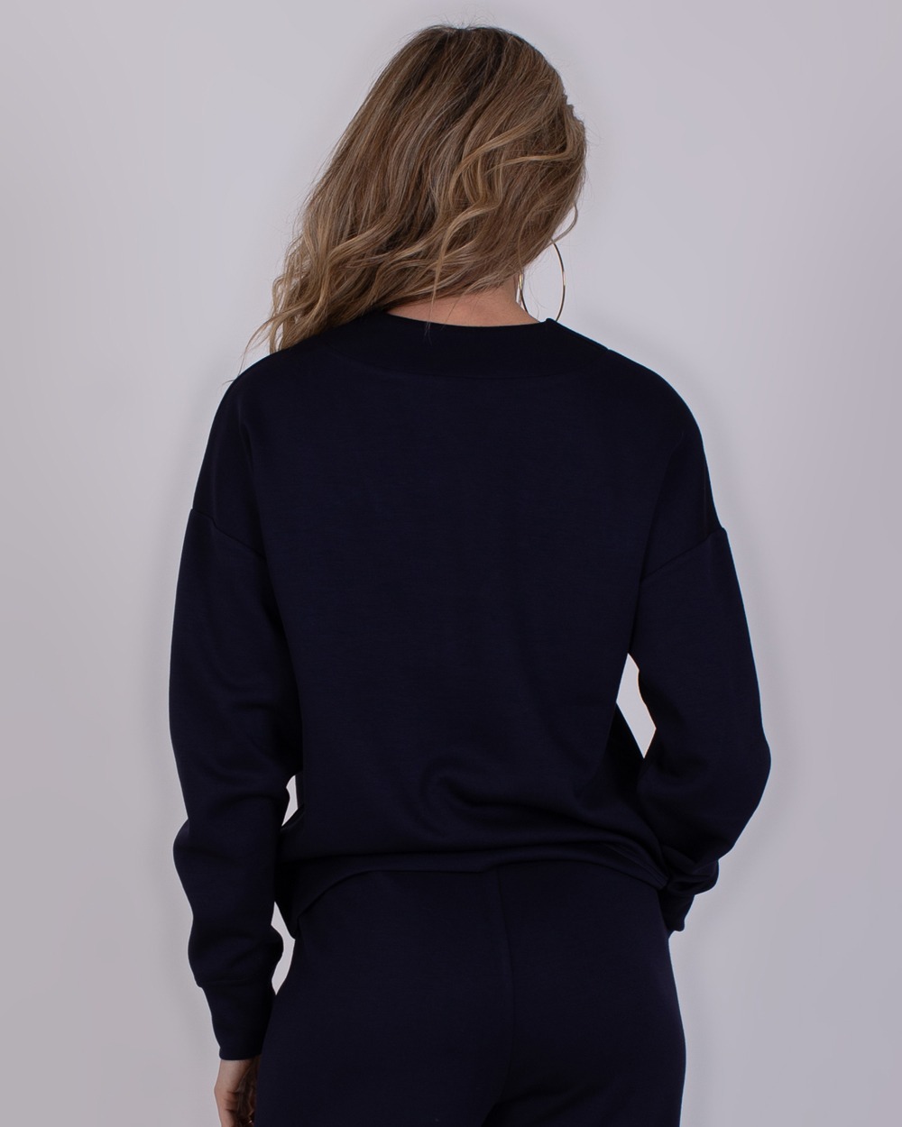 Chester navy 4 Achteraanzicht van een vrouw in een navykleurige Chester trui en broek.