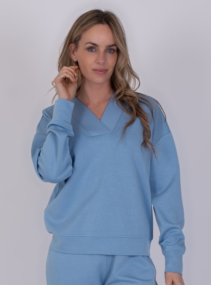 Vrouw draagt een comfortabele, lichtblauwe Chester-soft trui met bijpassende broek.