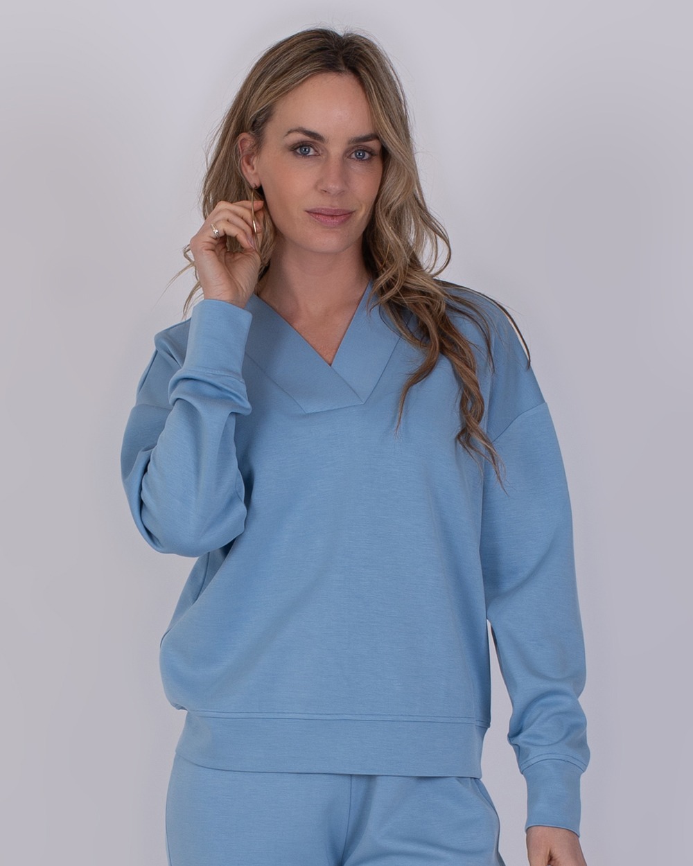 Chester soft blue 1 Vrouw draagt een comfortabele, lichtblauwe Chester-soft trui met bijpassende broek.