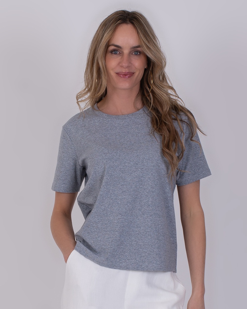 Vrouw draagt een grijs Denver T-shirt met korte mouwen en een witte broek.