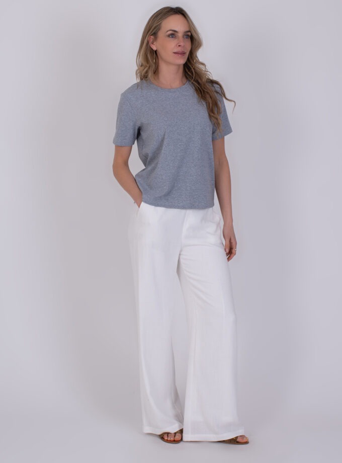 Vrouw draagt een grijs Denver Grey T-shirt met korte mouwen en witte, wijde broek.