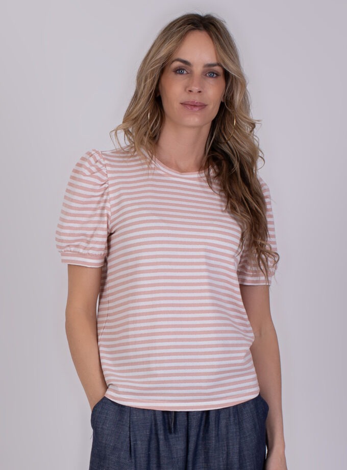 Vrouw draagt een Dhaka Stripe shirt met roze-witte strepen en korte pofmouwen.