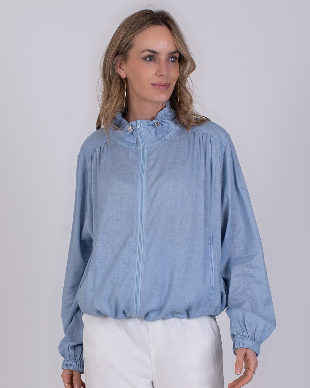 Edessa soft blue 6 Vrouw draagt een lichtblauwe Edessa soft blue jas met rits en opstaande kraag.