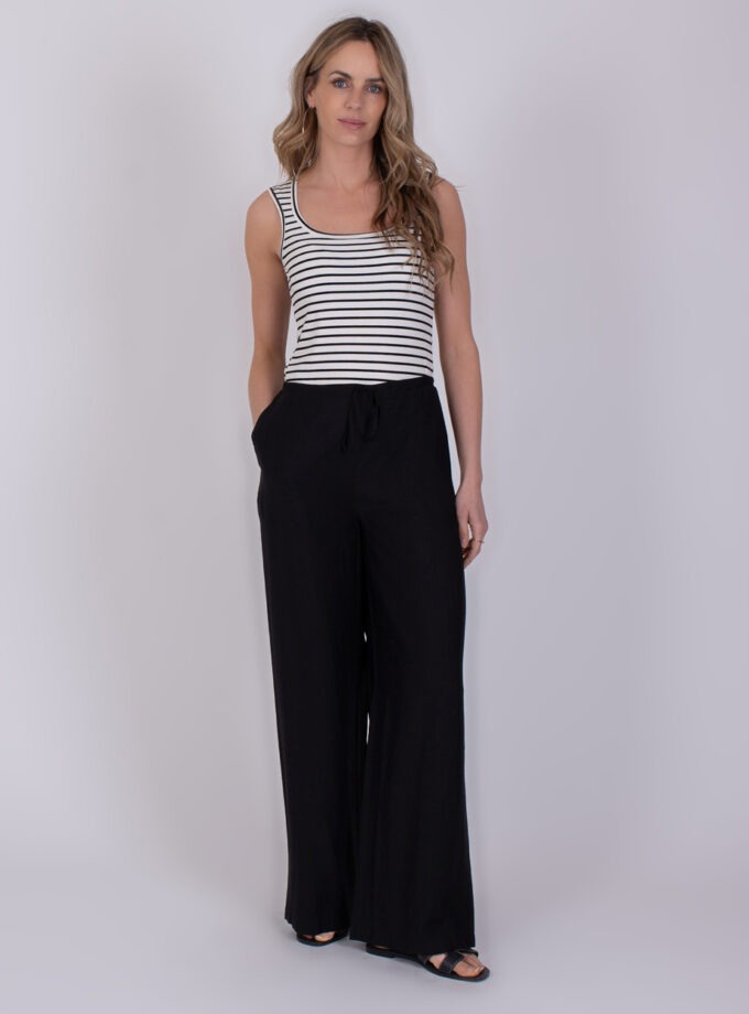Vrouw draagt een gestreept mouwloos topje en wijde zwarte Escada-broek.
