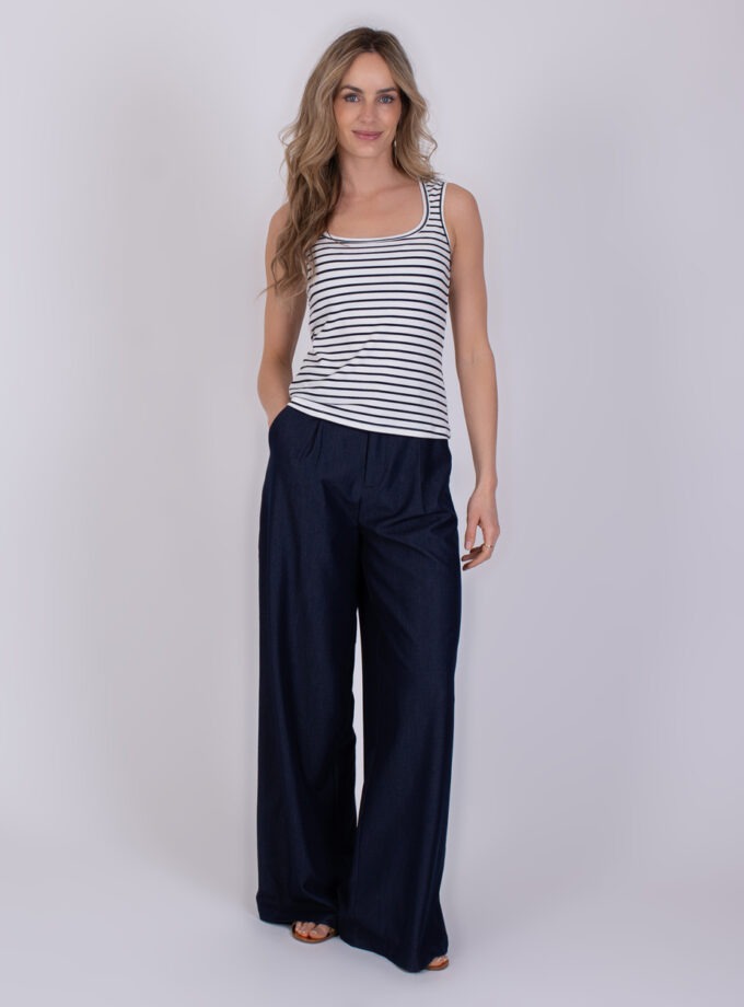 Vrouw draagt een mouwloos Felize gestreept navy-offwhite topje met wijde donkerblauwe broek.