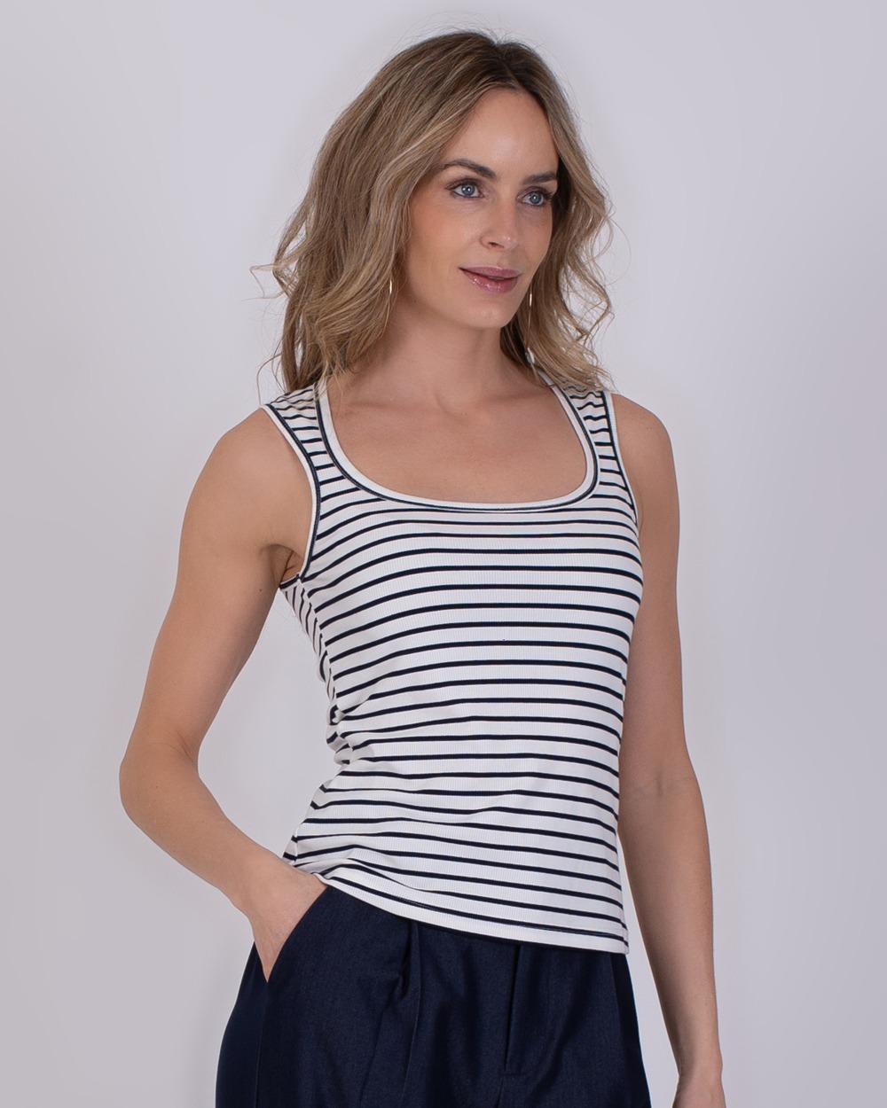 Vrouw draagt een mouwloos Felize-topje met navy-offwhite strepen en een ronde hals.