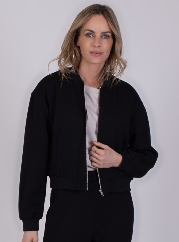 Vrouw draagt een zwarte Harlow bomberjack met zilverkleurige rits.