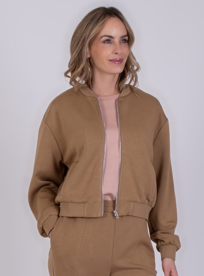 Vrouw draagt een taupekleurig Harlow-vest met bijpassende broek en een roze top.