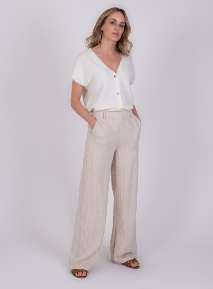 Vrouw draagt een licht, zomers outfit met een witte knoopblouse en beige linnen broek uit de Jeju Pale 2 collectie.