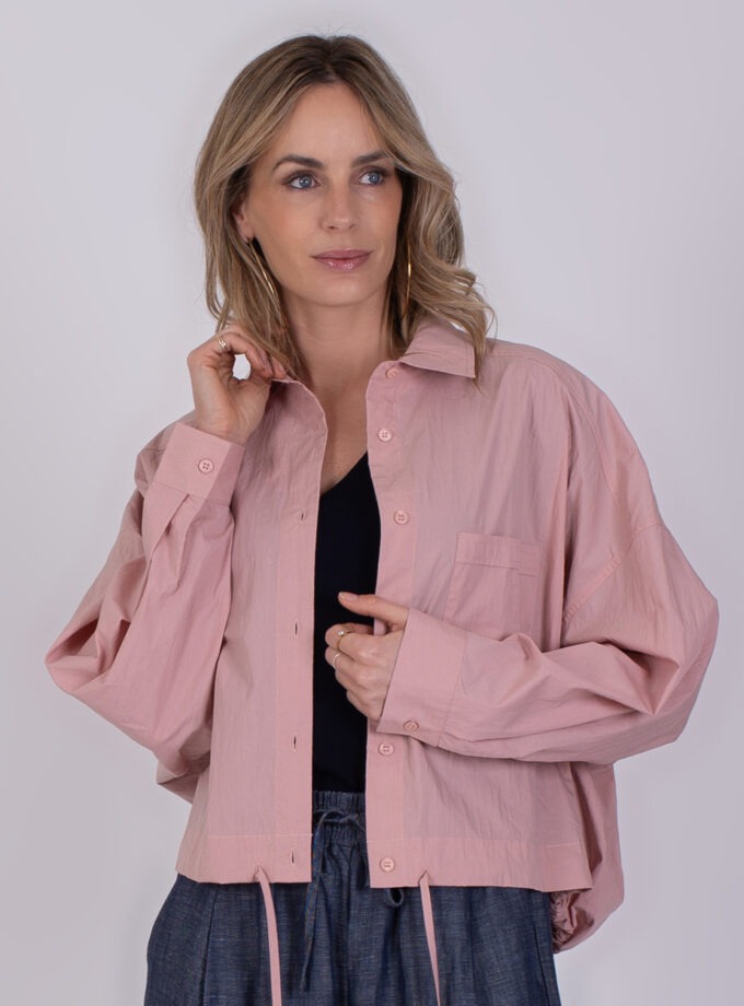 Vrouw draagt een oversized, lichtroze Juba Old Pink blouse met knopen en een borstzakje.