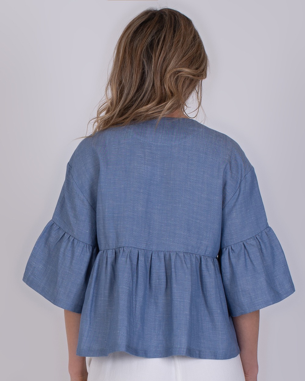 Khost light jeans blue 6 Achteraanzicht van een vrouw die een Khost lichtblauwe spijkerblouse met wijde mouwen draagt.