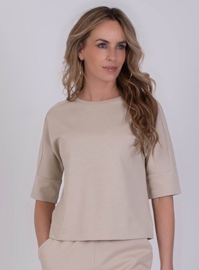 Vrouw draagt een beige Kiruna Pale 3 top met halflange mouwen.