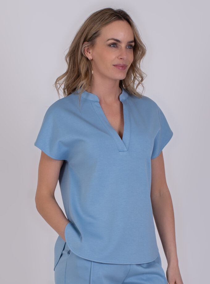 Vrouw draagt een lichtblauwe Laval soft blue top met korte mouwen en V-hals.