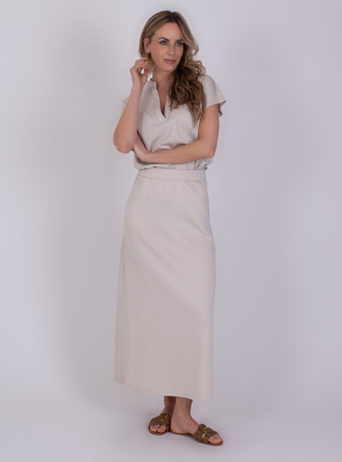 Vrouw poseert in een lichtbeige Linz Pale 1 maxi-jurk met korte mouwen en split bij de hals.