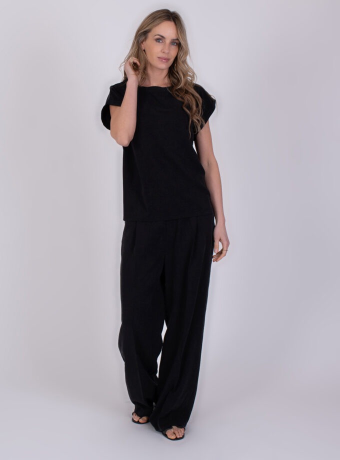 Vrouw draagt een zwarte Lodi-set met een losse top en wijde broek.