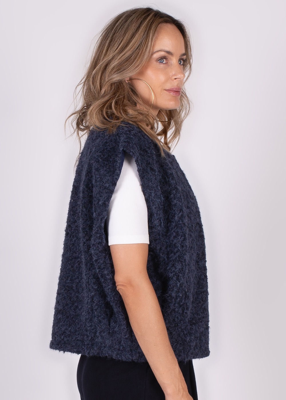 Model draagt een donkerblauw Matsumoto gilet en kijkt opzij tegen een neutrale achtergrond.