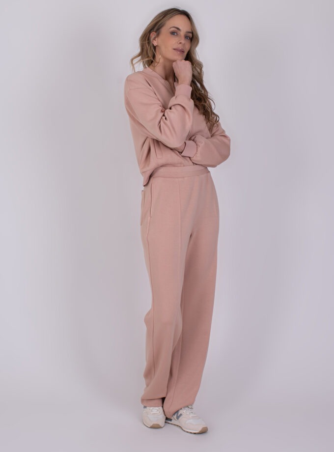 Vrouw poseert in een comfortabele, oudroze Mesuru loungetrainingsset met sneakers.