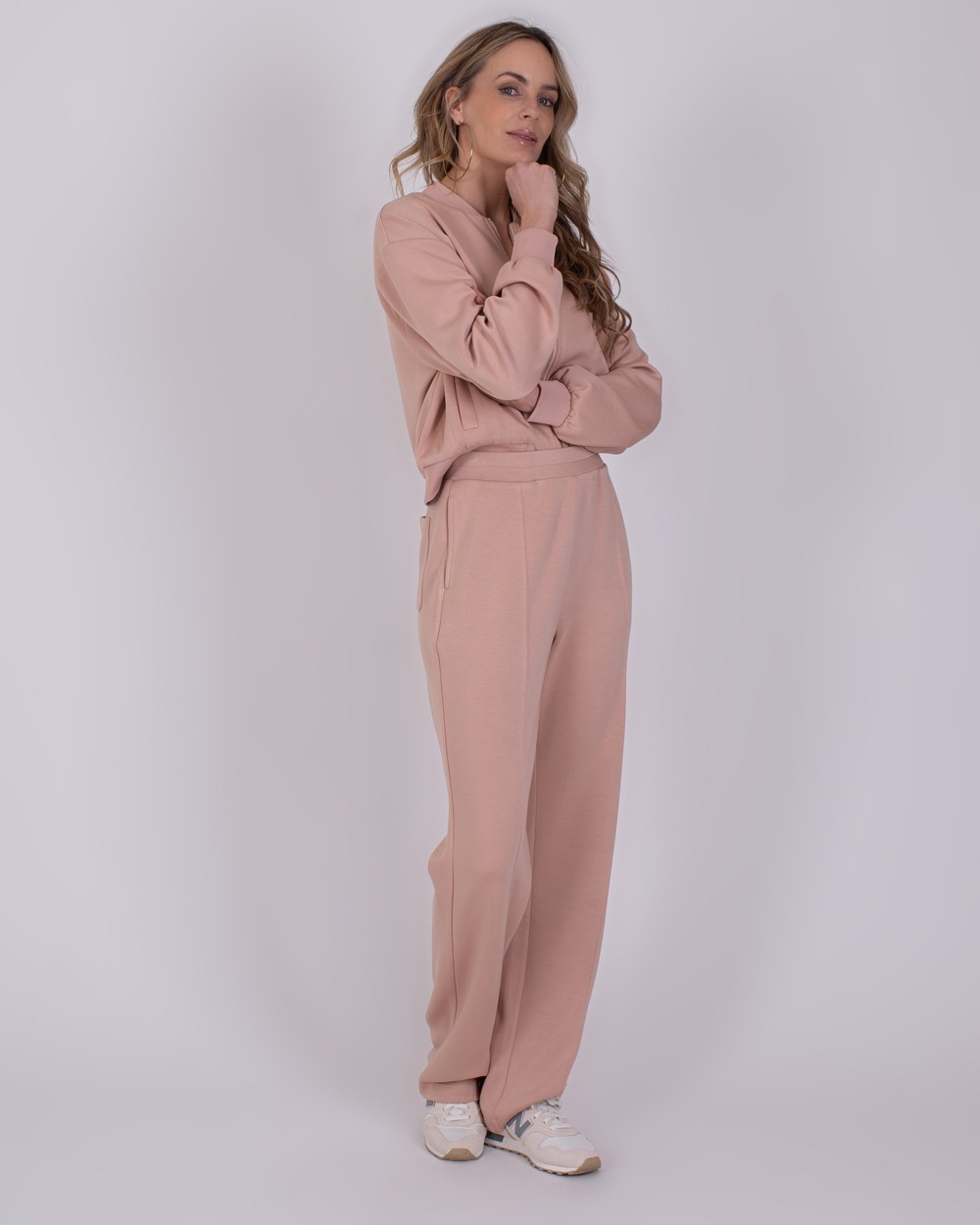 Vrouw poseert in een comfortabele, oudroze Mesuru loungetrainingsset met sneakers.