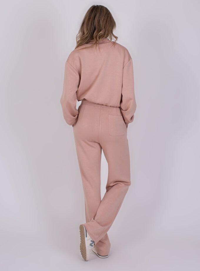 Vrouw gekleed in een comfortabele Mesuru old pink loungetrainingspak, gezien van achteren.