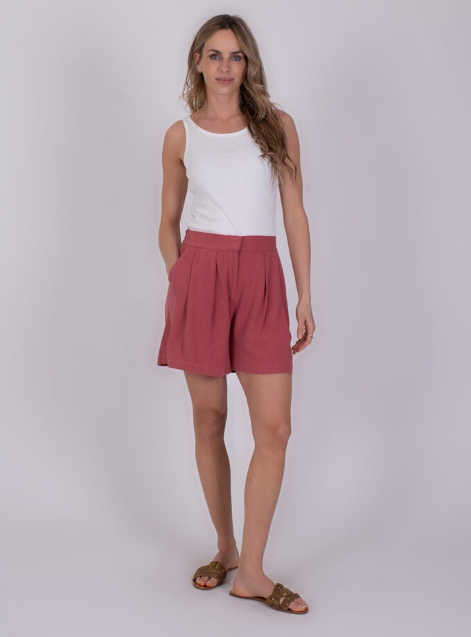 Vrouw draagt een witte tanktop en Patna raspberry-kleurige short met plooien.