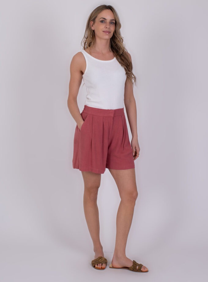 Vrouw draagt een witte tanktop en Patna raspberry shorts met plooien.