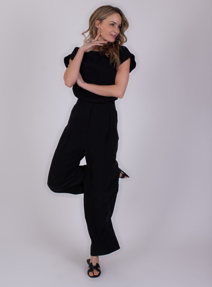 Vrouw poseert in een zwarte Piran Black 2 jumpsuit tegen een neutrale achtergrond.