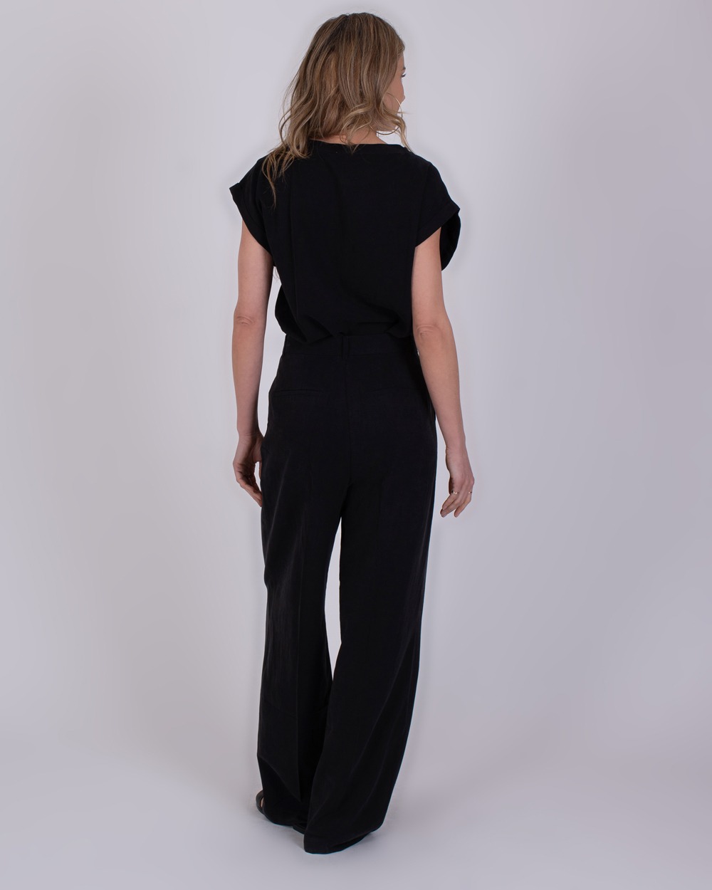 Piran black 4 Vrouw van achteren in een zwarte Piran Black 4 jumpsuit met korte mouwen en wijde pijpen.