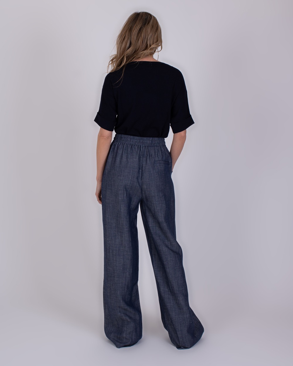 Pune medium blue 5 Vrouw van achteren in een donkerblauwe top en wijde Pune medium blue broek.