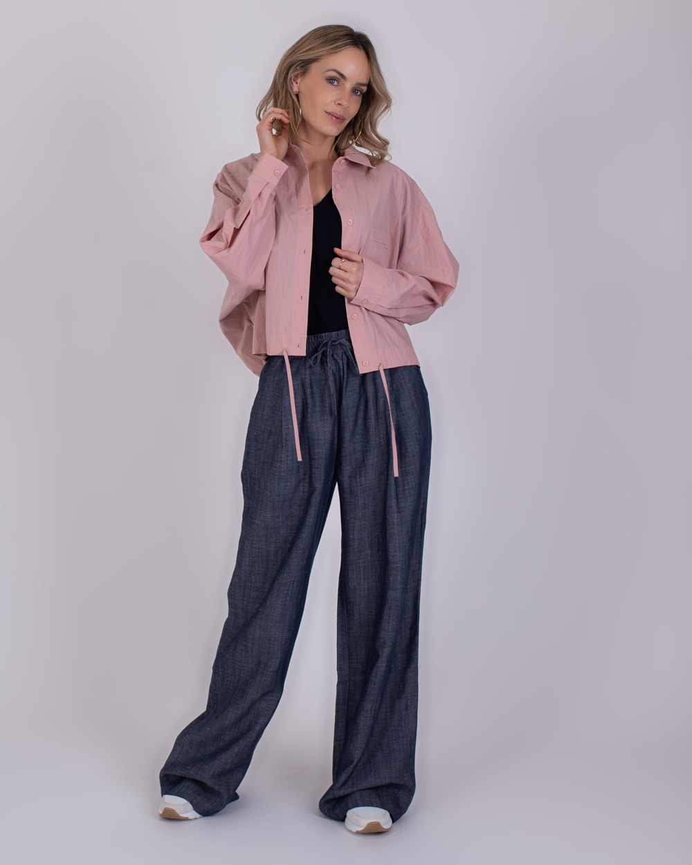 Pune medium blue 6 Vrouw draagt een roze blouse, zwart shirt en losse blauwe Pune medium blue 6 broek.