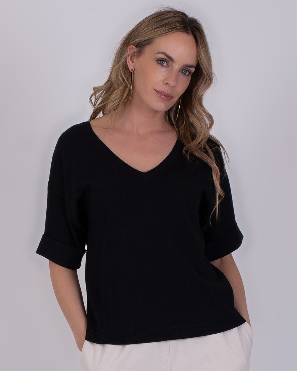 Vrouw draagt een zwarte Pylos black 2 top met V-hals en opgerolde mouwen.